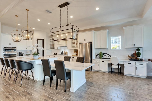 kitchen with a large island, a kitchen breakfast bar, a chandelier, and stainless steel appliances