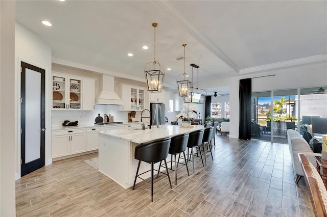 kitchen with custom range hood, cooktop, open floor plan, and freestanding refrigerator