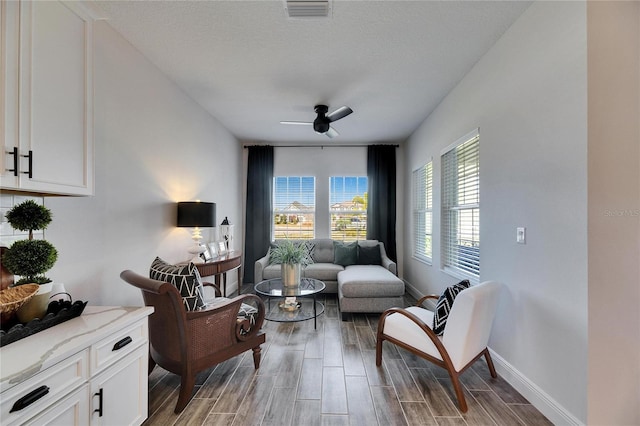 living area with baseboards, a textured ceiling, visible vents, wood tiled floor, and ceiling fan