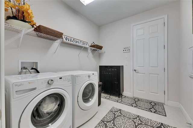 washroom with light tile patterned floors, independent washer and dryer, laundry area, and baseboards