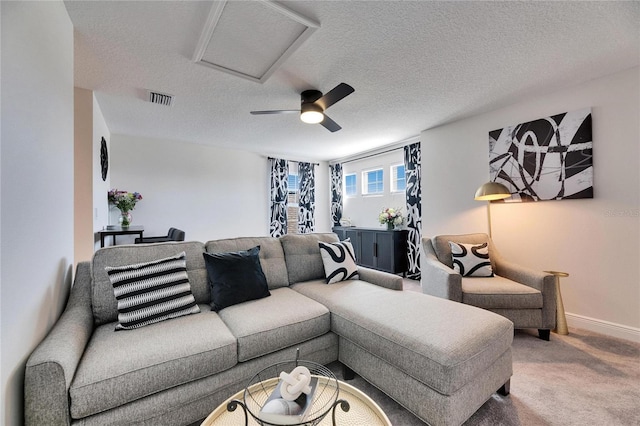 living room with baseboards, a textured ceiling, attic access, visible vents, and carpet