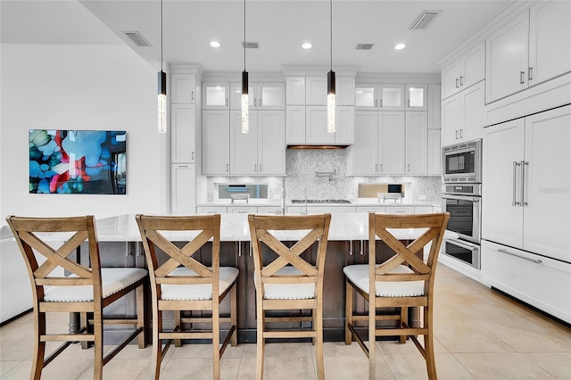 6113 Pasadena Point Blvd, Gulfport, FL 33707 - kitchen featuring built in appliances, decorative backsplash, glass insert cabinets, light tile patterned floors, and an island with sink