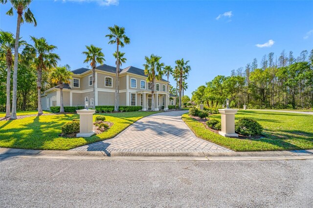 view of front of home featuring stucco siding, a front lawn, and decorative driveway