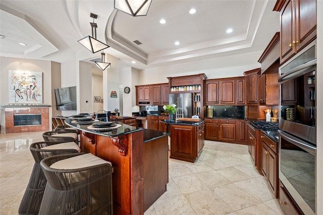 19005 Cour Ests, Lutz, FL 33558 - kitchen with a raised ceiling, a center island with sink, stainless steel appliances, dark countertops, and recessed lighting
