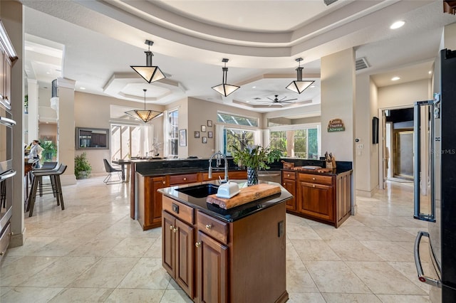 19005 Cour Ests, Lutz, FL 33558 - kitchen featuring a tray ceiling, brown cabinets, a sink, a ceiling fan, and a center island with sink