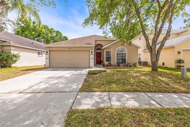 view of front of house featuring a front yard, cooling unit, driveway, an attached garage, and stucco siding