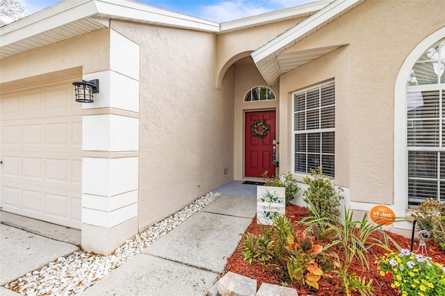 doorway to property featuring stucco siding and a garage