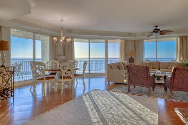 living area with ornamental molding, wood finished floors, and ceiling fan with notable chandelier