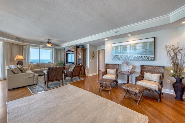 living area featuring a textured ceiling, crown molding, and a ceiling fan
