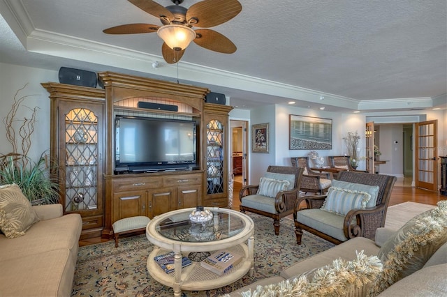 living area featuring light wood-type flooring, a ceiling fan, ornamental molding, and a textured ceiling