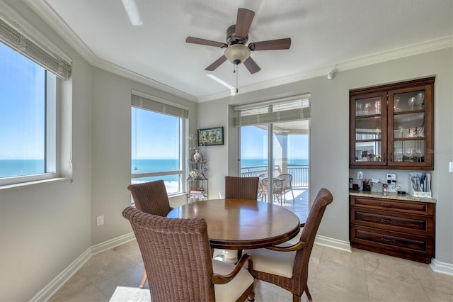 dining area with crown molding, baseboards, a ceiling fan, and bar