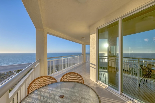 balcony featuring outdoor dining area and a water view