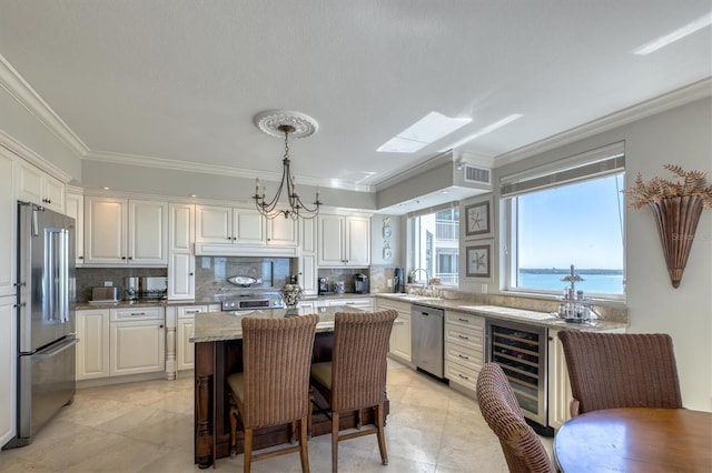 kitchen featuring stainless steel appliances, a center island, beverage cooler, and ornamental molding