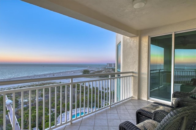 balcony at dusk featuring a water view