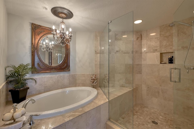 bathroom with a shower stall, a bath, and a chandelier