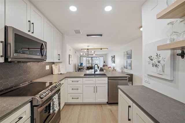 6277 Bahia Del Mar Blvd Unit 210, Saint Petersburg, FL 33715 - kitchen featuring stainless steel appliances, a sink, a peninsula, backsplash, and white cabinets