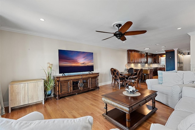 living area featuring baseboards, a ceiling fan, crown molding, and light wood-style floors