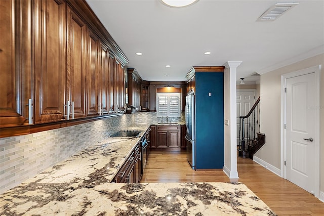 kitchen with visible vents, light wood-style flooring, light stone counters, freestanding refrigerator, and black electric stovetop
