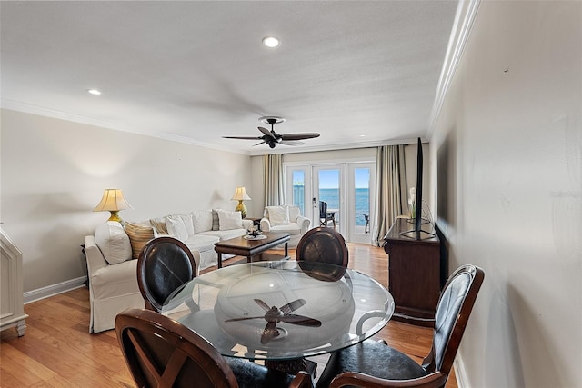 dining area with light wood-type flooring, a ceiling fan, and crown molding