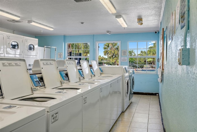 common laundry area with light tile patterned floors, plenty of natural light, washer and dryer, and a textured ceiling