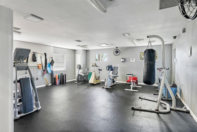 gym with visible vents, baseboards, and a textured ceiling