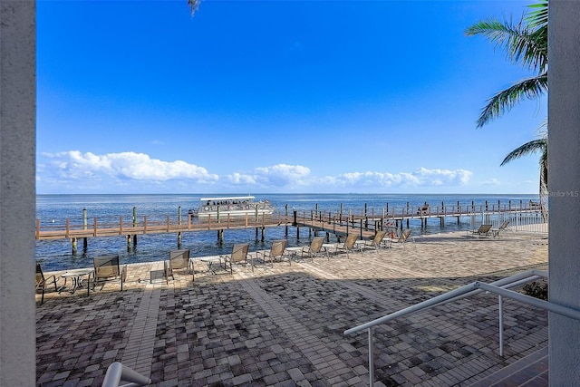 view of patio / terrace featuring a view of the beach, a water view, and a boat dock