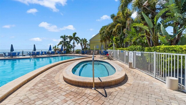 pool with a community hot tub, a patio, and fence