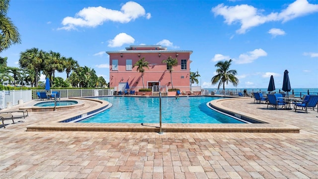 community pool featuring a patio, fence, and a hot tub