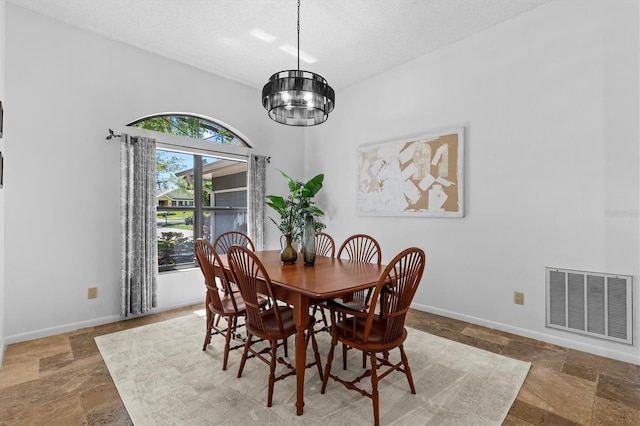 dining space with stone tile floors, baseboards, visible vents, an inviting chandelier, and a textured ceiling