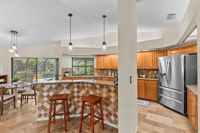 kitchen with visible vents, a breakfast bar, light stone counters, stone tile flooring, and appliances with stainless steel finishes