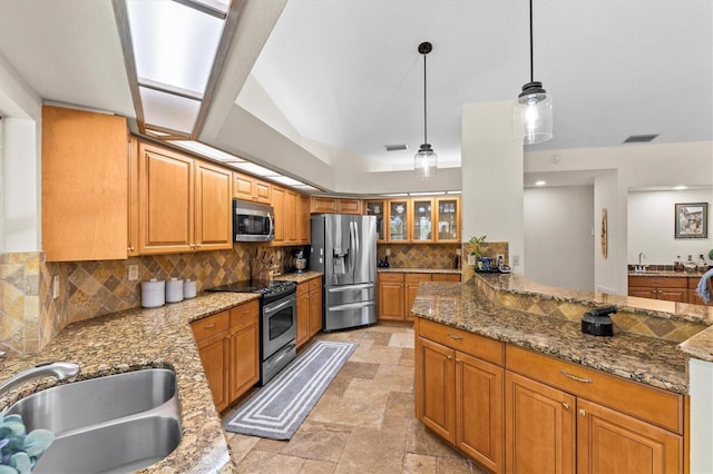 kitchen featuring tasteful backsplash, stone finish floor, stone countertops, stainless steel appliances, and a sink