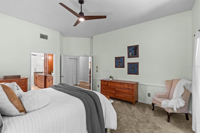 bedroom featuring a ceiling fan, visible vents, a textured ceiling, light carpet, and connected bathroom