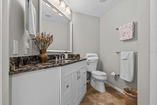 bathroom featuring toilet, vanity, and baseboards