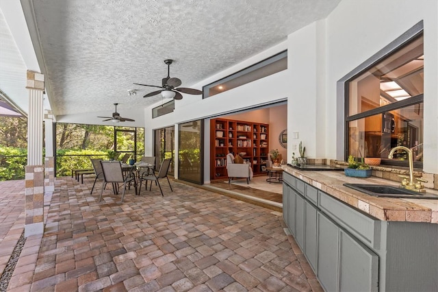 view of patio featuring outdoor dining space, an outdoor kitchen, ceiling fan, and a sink