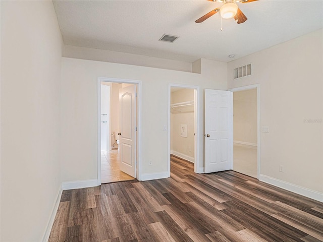 405 Laguna Mill Dr, Ruskin, FL 33570 - unfurnished bedroom featuring dark wood-style floors, a spacious closet, a closet, and a ceiling fan