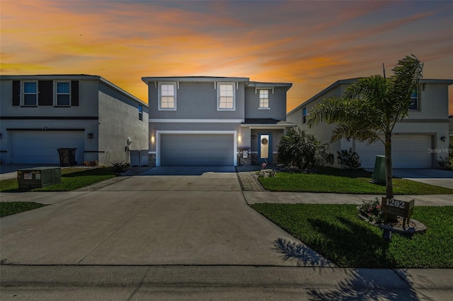 traditional-style home with stucco siding, a lawn, stone siding, concrete driveway, and an attached garage