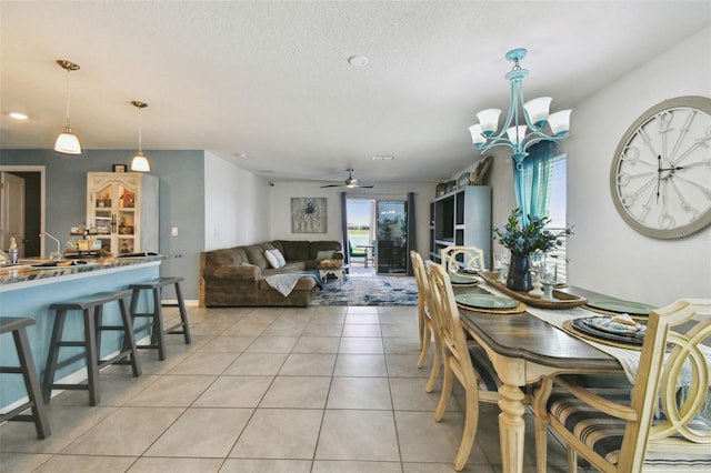 dining area with light tile patterned flooring, ceiling fan with notable chandelier, and a textured ceiling