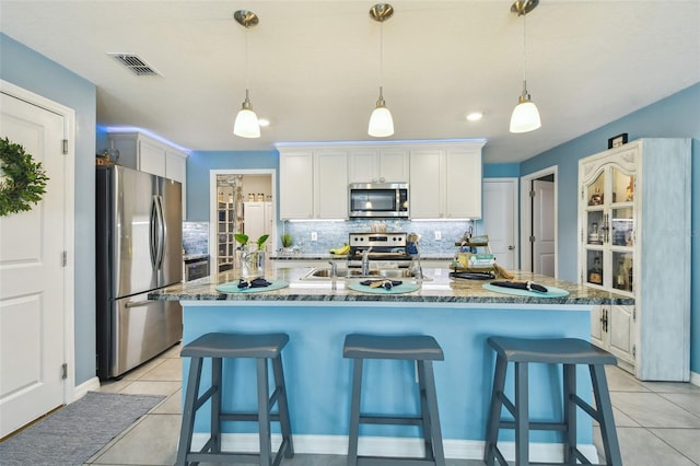 kitchen featuring visible vents, light tile patterned flooring, stainless steel appliances, white cabinetry, and tasteful backsplash