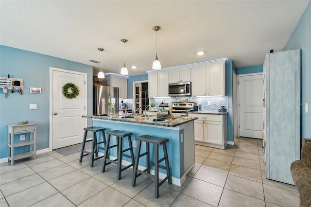kitchen with backsplash, white cabinetry, dark stone counters, appliances with stainless steel finishes, and light tile patterned floors
