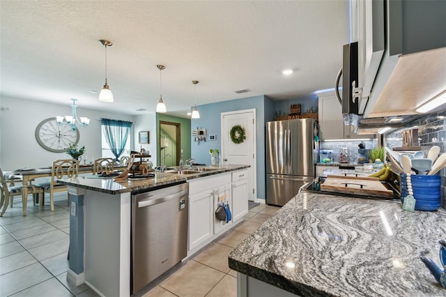 kitchen with an island with sink, a sink, backsplash, white cabinetry, and appliances with stainless steel finishes