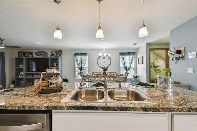kitchen featuring open floor plan, pendant lighting, an inviting chandelier, white cabinetry, and a sink