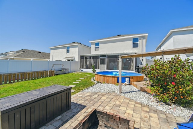 back of property with a fenced backyard, a sunroom, stucco siding, a patio area, and a lawn