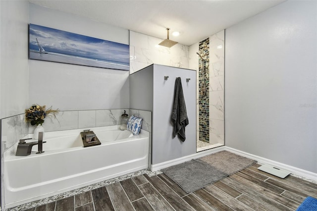 full bathroom with wood finish floors, baseboards, a bath, and a tile shower