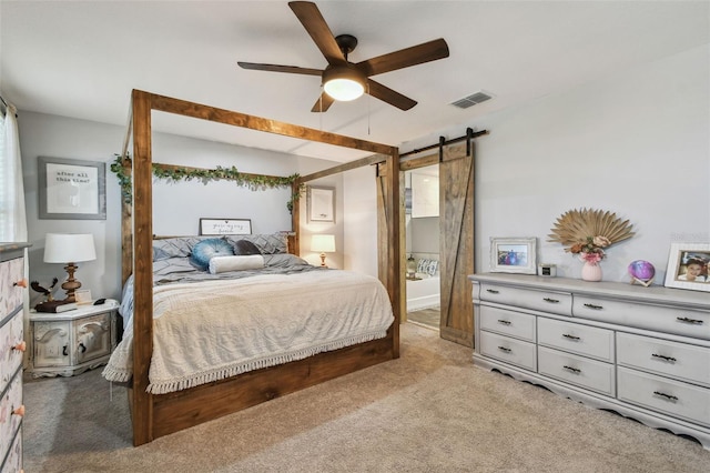 bedroom featuring visible vents, light carpet, ceiling fan, and a barn door