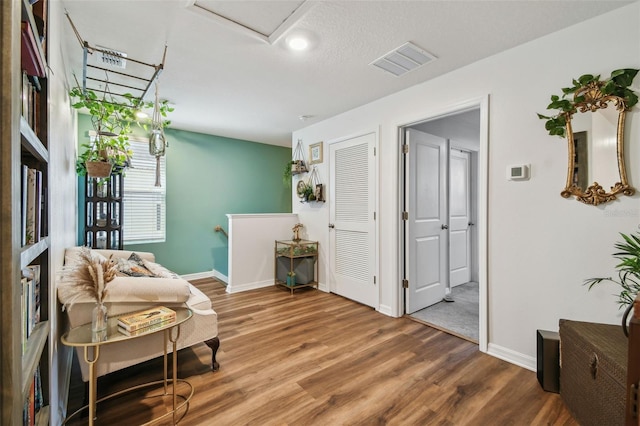 living area with wood finished floors, visible vents, and baseboards