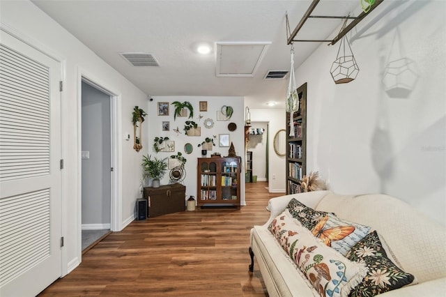 bedroom featuring visible vents, attic access, baseboards, and wood finished floors