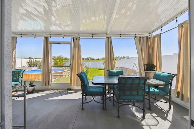 sunroom / solarium featuring a jacuzzi, plenty of natural light, a water view, and concrete flooring