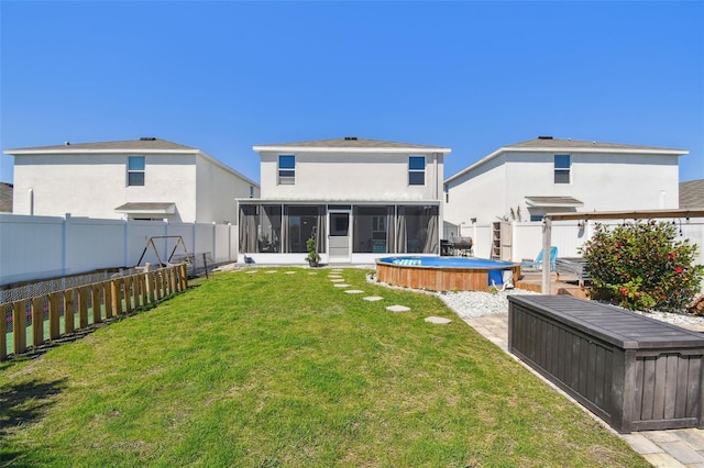 rear view of house with a yard, a fenced backyard, stucco siding, and a sunroom