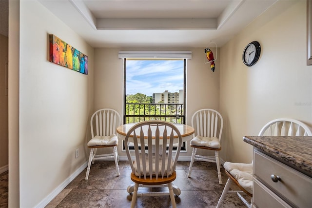 dining space featuring a tray ceiling and baseboards