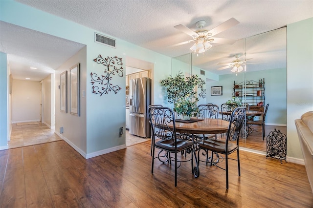 dining area with visible vents, a textured ceiling, ceiling fan, and wood finished floors